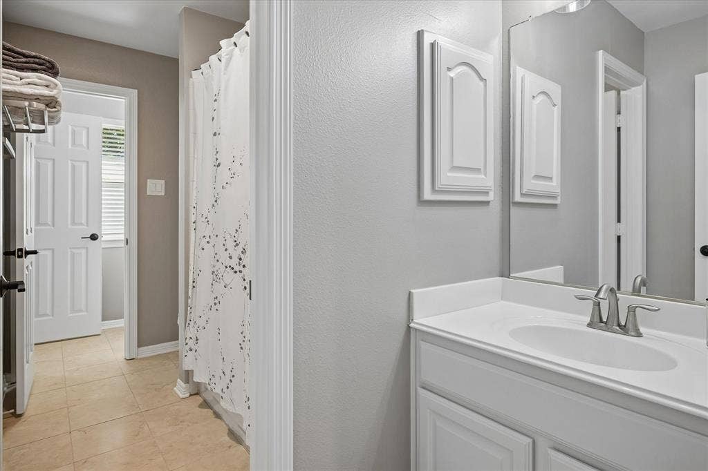 7525 Cedar Elm Drive, Irving, TX 75063 White vanity with a single basin sink, brushed nickel faucet, and a large wall-mounted mirror