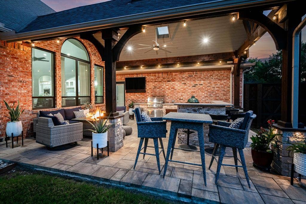 7525 Cedar Elm Drive, Irving, TX 75063 Covered outdoor living space featuring brick exterior, paver patio, wood beam ceiling, built-in outdoor kitchen, and arched windows