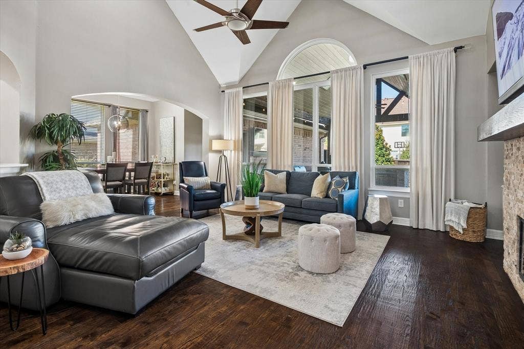7525 Cedar Elm Drive, Irving, TX 75063 Vaulted ceiling with a ceiling fan, dark wood-finish flooring, stone-clad fireplace with a wood mantel, and tall windows