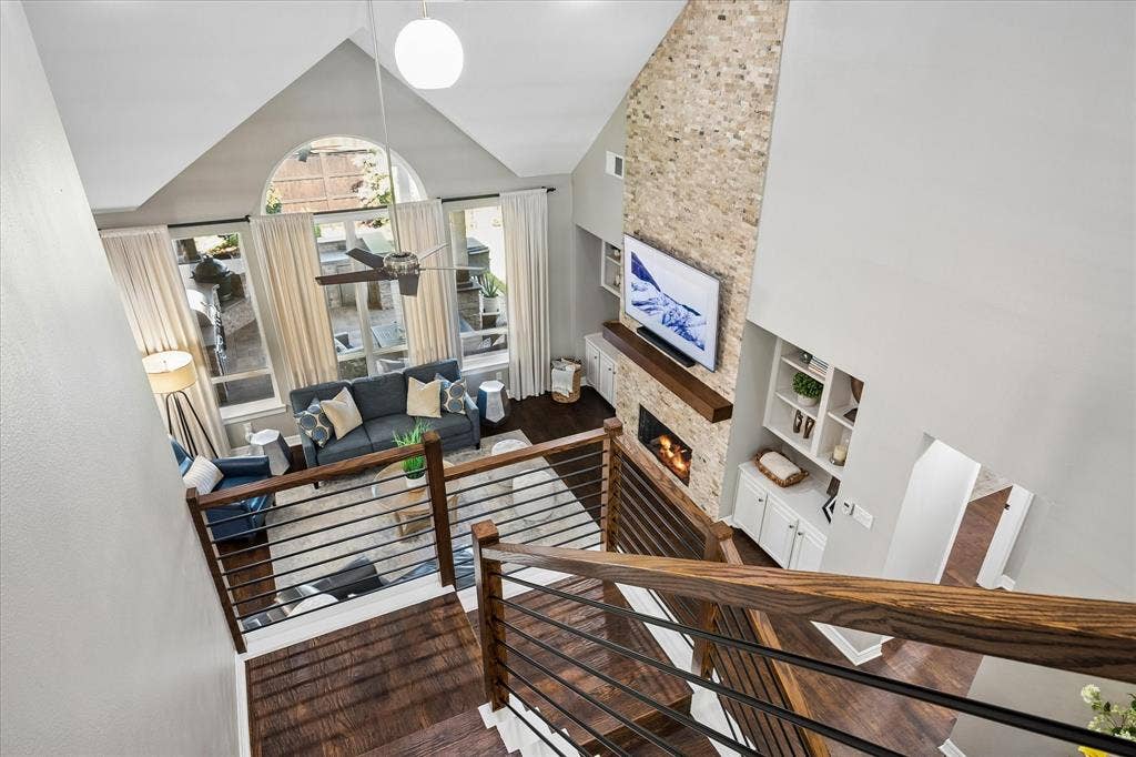 7525 Cedar Elm Drive, Irving, TX 75063 Two-story living area with a stone-clad fireplace, integrated shelving, and large windows