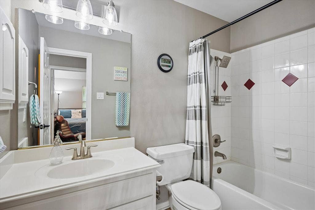 7525 Cedar Elm Drive, Irving, TX 75063 White vanity with integrated sink, brushed nickel faucet, large mirror, and three-light fixture