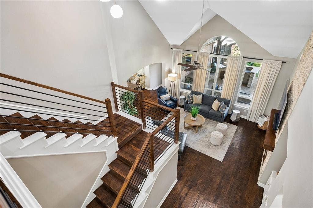 7525 Cedar Elm Drive, Irving, TX 75063 Vaulted ceilings with an arched window, wood-finish flooring, staircase with metal spindles, and a ceiling fan