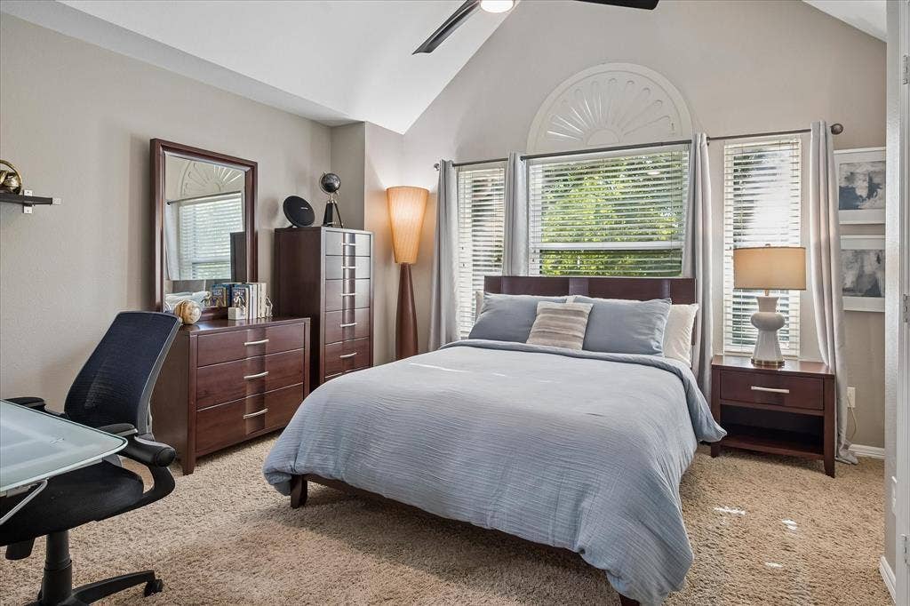7525 Cedar Elm Drive, Irving, TX 75063 Vaulted ceiling with an overhead fan, arched window with decorative trim, multiple windows with blinds, and carpet flooring