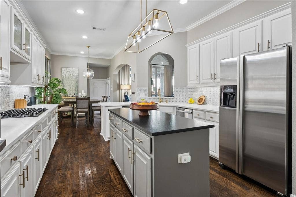 7525 Cedar Elm Drive, Irving, TX 75063 Gourmet kitchen with white cabinetry, dark wood-finish flooring, stainless steel appliances, a center island with a dark countertop, and recessed lighting