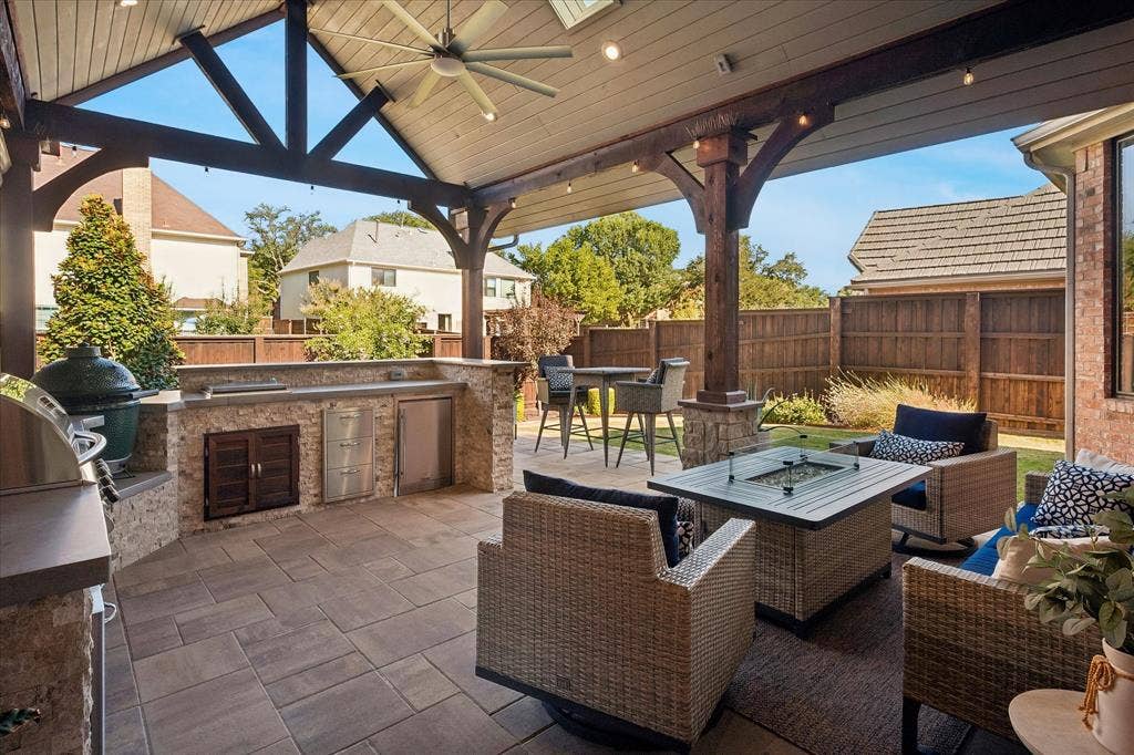 7525 Cedar Elm Drive, Irving, TX 75063 Covered patio featuring a slatted ceiling, exposed wood beams, a built-in outdoor kitchen with stone veneer, and paver flooring