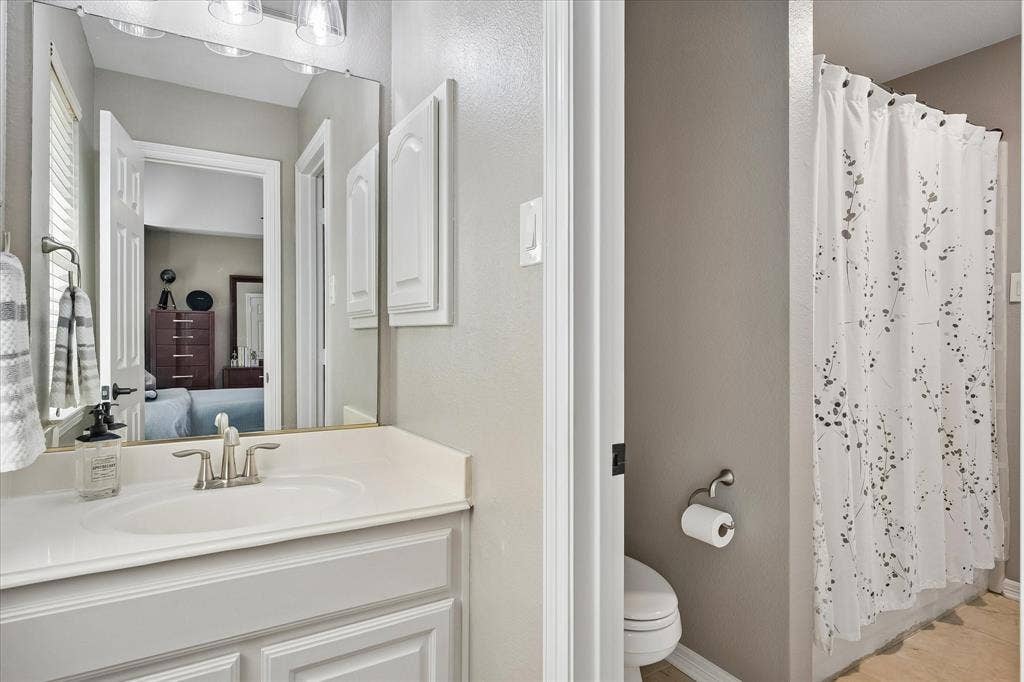 7525 Cedar Elm Drive, Irving, TX 75063 White vanity with integrated sink, brushed nickel faucet, wall-mounted mirror, and overhead lighting