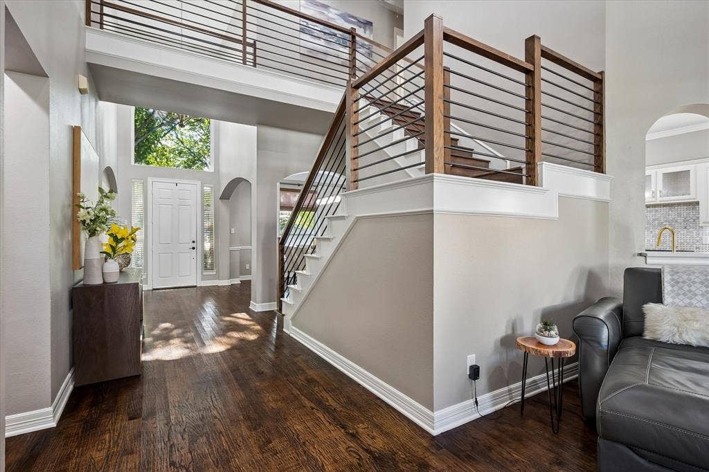 7525 Cedar Elm Drive, Irving, TX 75063 Two-story entryway with wood-finish flooring, a modern wood and metal staircase, arched doorways, and a transom window above the entry door