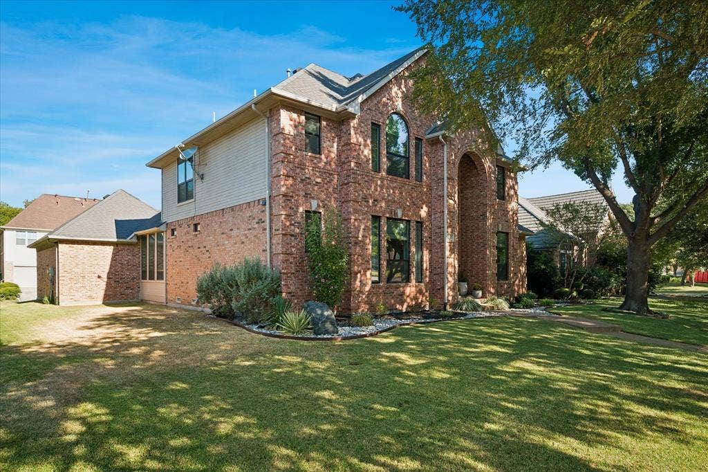 7525 Cedar Elm Drive, Irving, TX 75063 Brick exterior with an arched entryway, multiple windows, and a manicured lawn