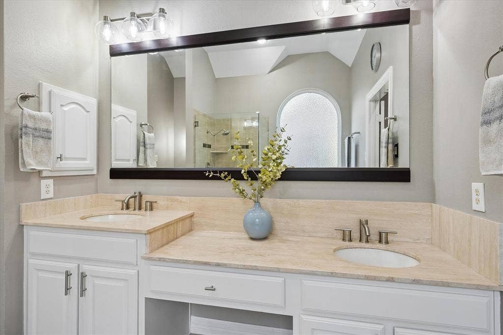 7525 Cedar Elm Drive, Irving, TX 75063 Dual vanity with light-toned countertops, white cabinetry, undermount sinks, and brushed nickel fixtures