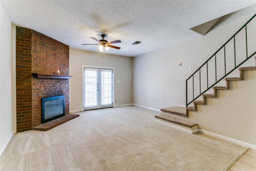 238 Samuel Boulevard, #1T, Coppell, TX 75019 Brick fireplace with wood mantel, glass-front fireplace insert, and brick hearth