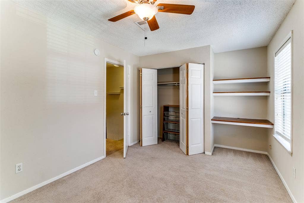 238 Samuel Boulevard, #1T, Coppell, TX 75019 Carpeted room featuring a ceiling fan, a bi-fold closet, and built-in shelving with a desk surface