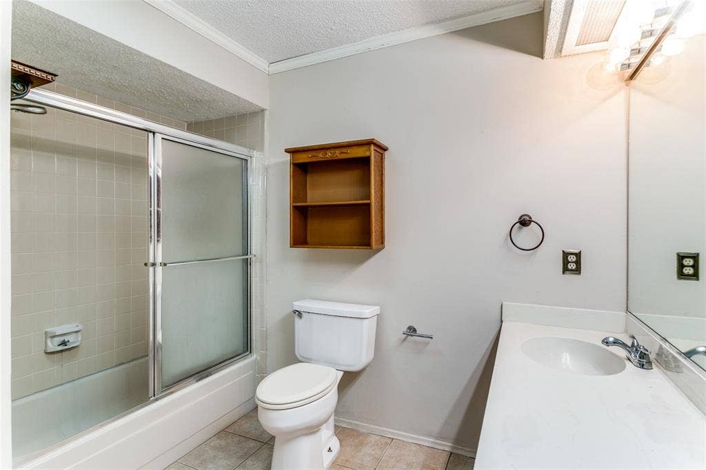 238 Samuel Boulevard, #1T, Coppell, TX 75019 Bathtub with sliding shower doors, single vanity with integrated sink, wall-mounted mirror, and tile flooring