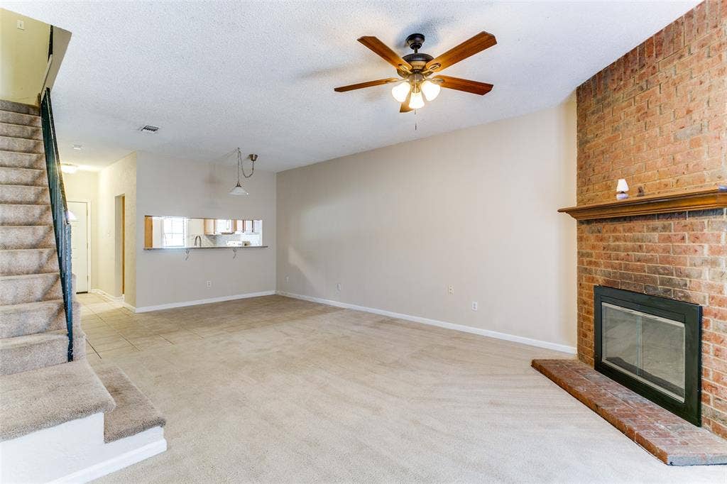 238 Samuel Boulevard, #1T, Coppell, TX 75019 Brick-clad fireplace with a wood mantle, ceiling fan with integrated lighting, and a pass-through window with a breakfast bar