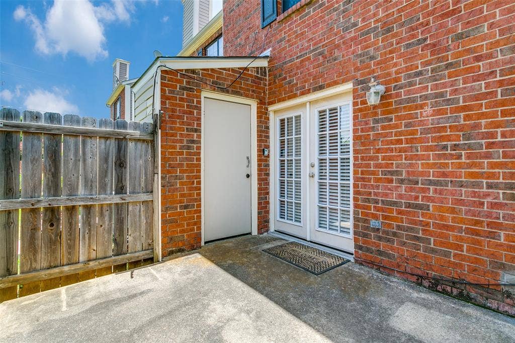 238 Samuel Boulevard, #1T, Coppell, TX 75019 Brick exterior with a privacy fence, concrete patio, and white French doors