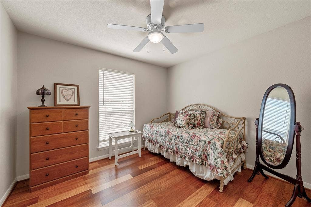 Wood-finish flooring, single window with blinds, ceiling fan, and light-toned wall paint