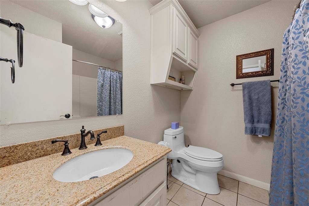 Bathroom vanity with a granite-look countertop, integrated oval sink, and dark bronze-finish fixtures
