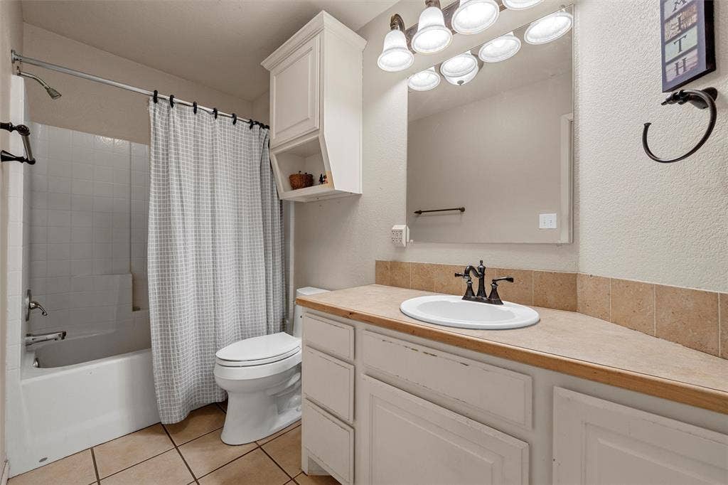 White vanity with an integrated sink, bronze-finish faucet, and a stone-look countertop with a tile backsplash