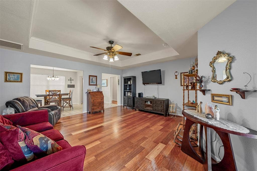 Hardwood-finish flooring, tray ceiling with crown molding, ceiling fan with integrated lighting, recessed wall opening