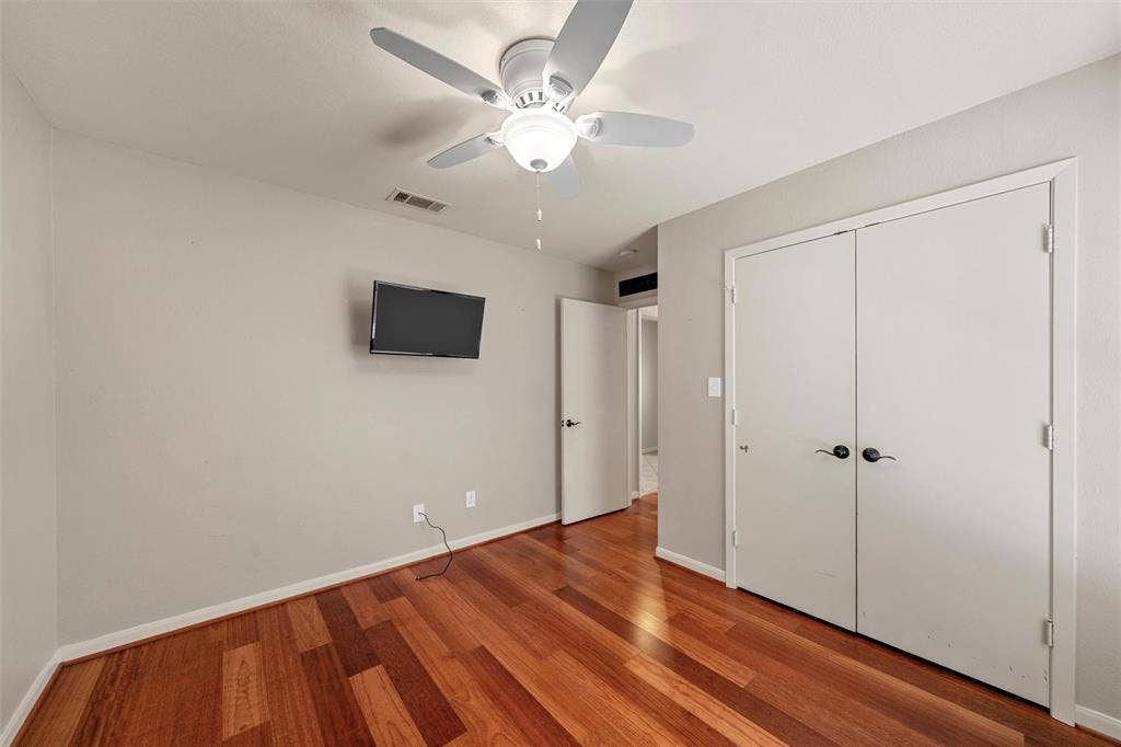 Hardwood-style flooring, neutral wall tones, and a ceiling fan with integrated lighting