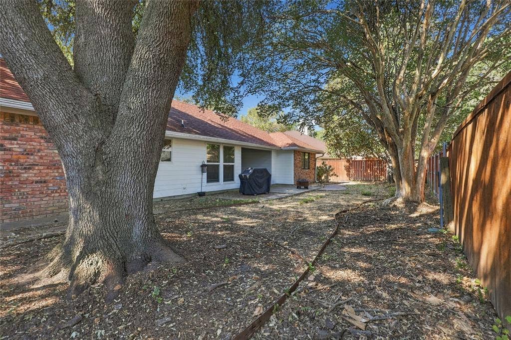 1309 Oxford Lane, Denton, TX 76209 Spacious backyard featuring mature trees, a red brick exterior, white siding, and a wood privacy fence