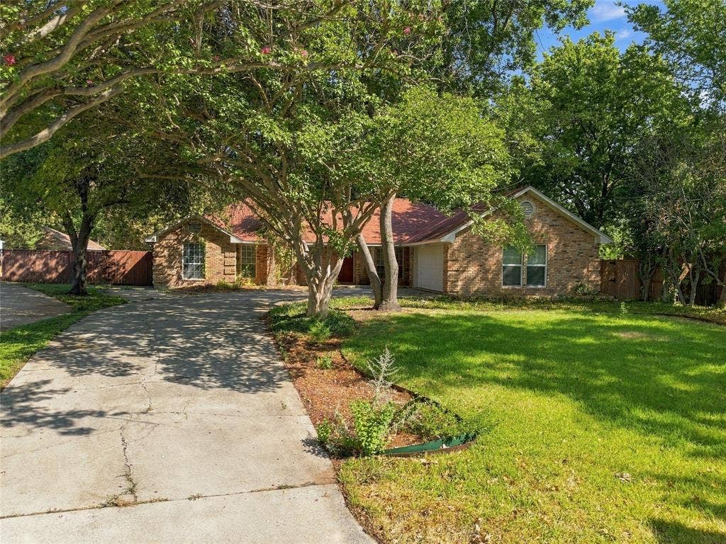 1309 Oxford Lane, Denton, TX 76209 Brick exterior with a covered entry, mature trees, and an expansive front lawn