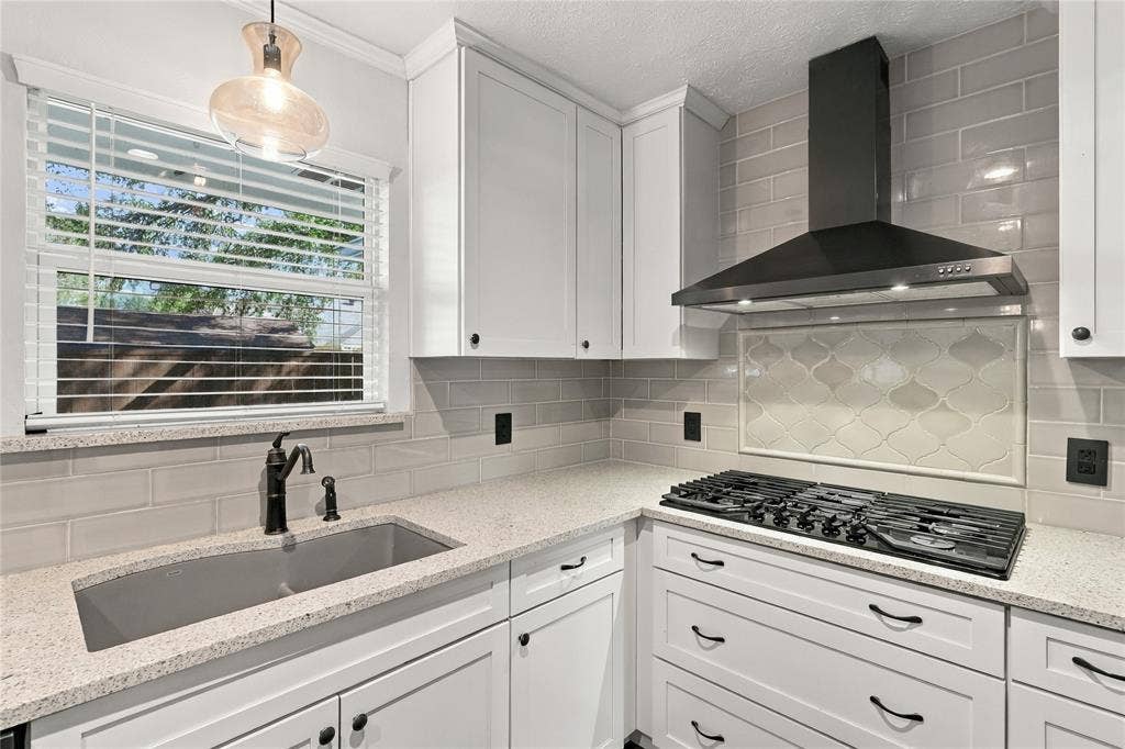 1309 Oxford Lane, Denton, TX 76209 White shaker cabinetry, light-toned countertops, gas cooktop, black range hood, and subway tile backsplash