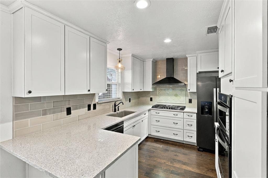 1309 Oxford Lane, Denton, TX 76209 White shaker cabinetry, light-toned countertops, subway tile backsplash, dark wood-finish flooring, and stainless steel appliances