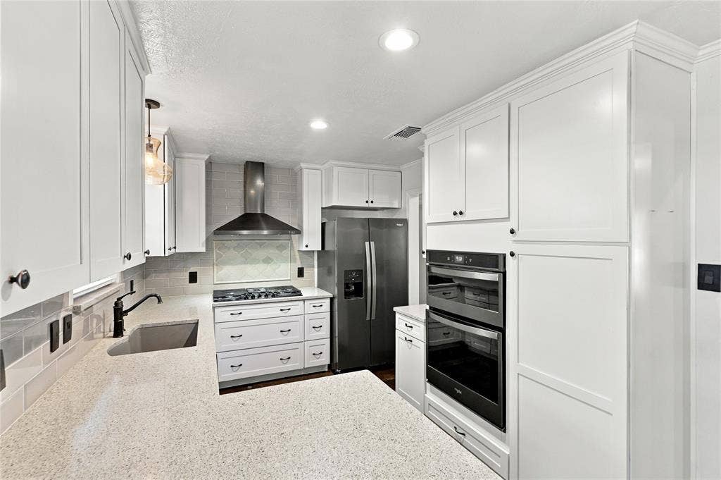 1309 Oxford Lane, Denton, TX 76209 White shaker-style cabinetry, stainless steel appliances, quartz countertops, tile backsplash, and recessed lighting
