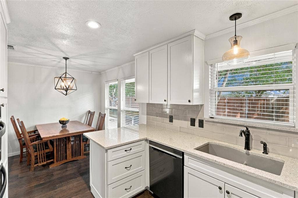1309 Oxford Lane, Denton, TX 76209 White cabinetry with dark hardware, stone countertops, subway tile backsplash, stainless steel sink with a dark faucet, and wood-finish flooring