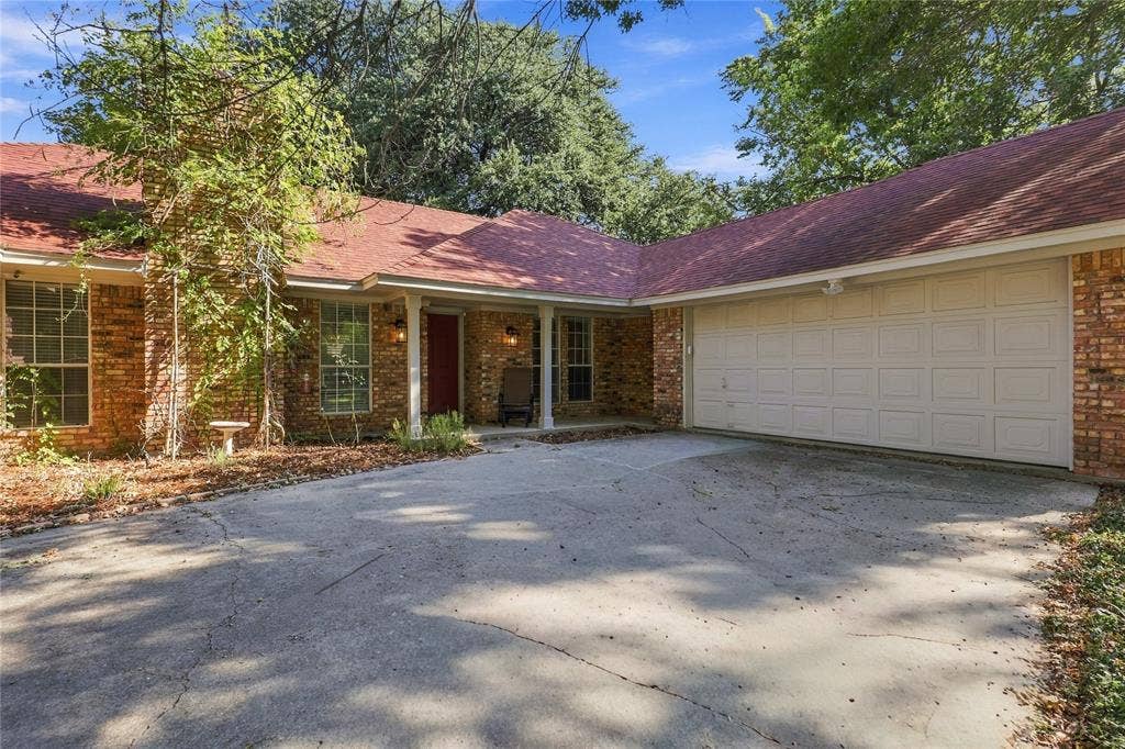 1309 Oxford Lane, Denton, TX 76209 Brick exterior with a covered entry, attached garage, and a concrete driveway