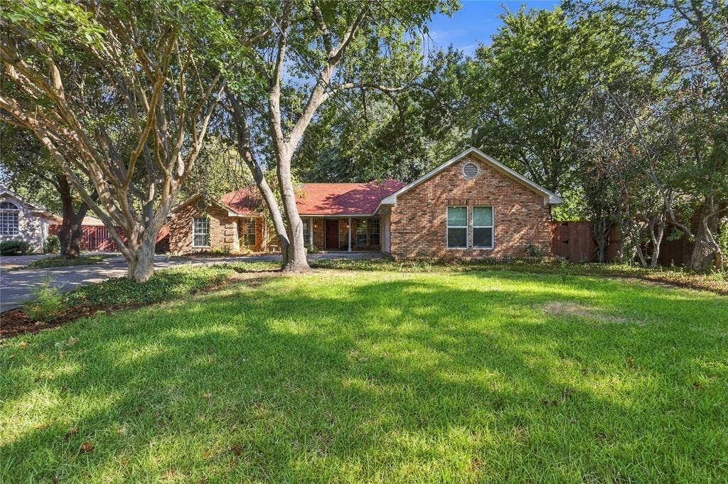 1309 Oxford Lane, Denton, TX 76209 Brick exterior with a red roof, front yard, and mature trees