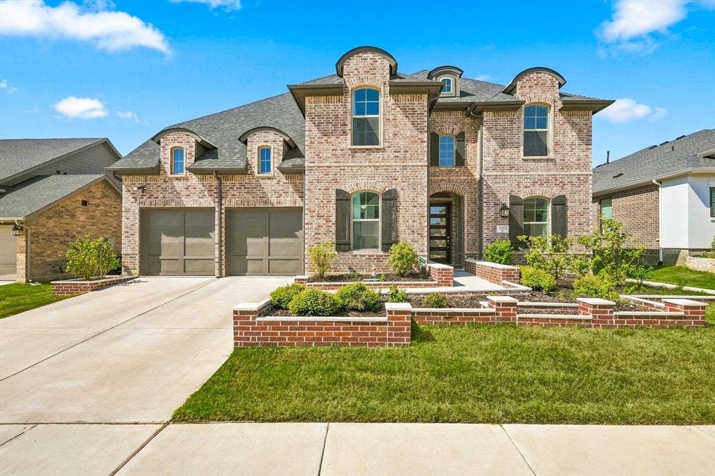 2812 Dunbar Drive, Northlake, TX 76247 Brick exterior with a multi-gabled roofline, two-car garage, and tiered landscaping beds