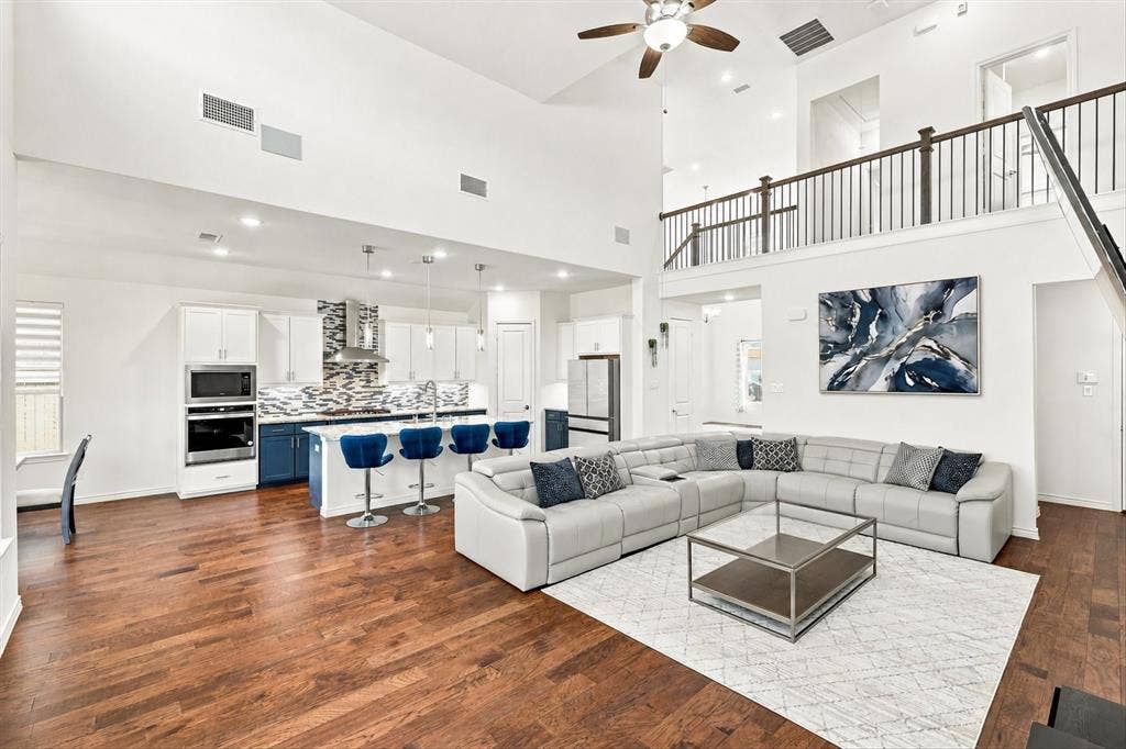 2812 Dunbar Drive, Northlake, TX 76247 Vaulted ceilings, wood-finish flooring, a kitchen island with pendant lighting, a stainless steel range hood, and a second-story interior balcony