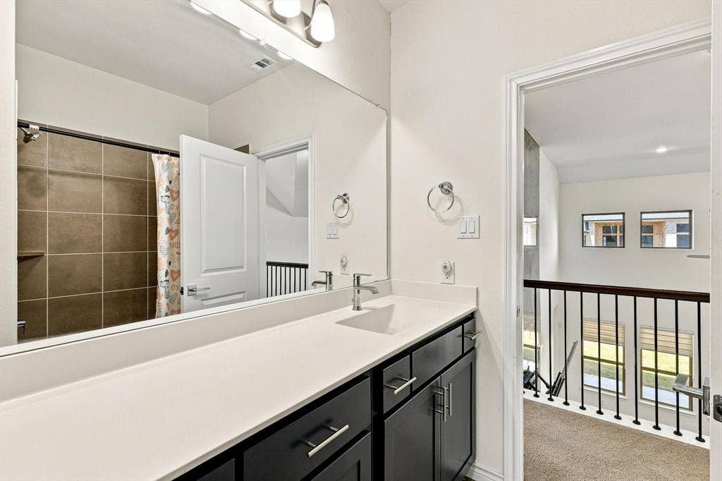 2812 Dunbar Drive, Northlake, TX 76247 Modern bathroom vanity with a long white countertop, dark cabinetry, and dual sinks