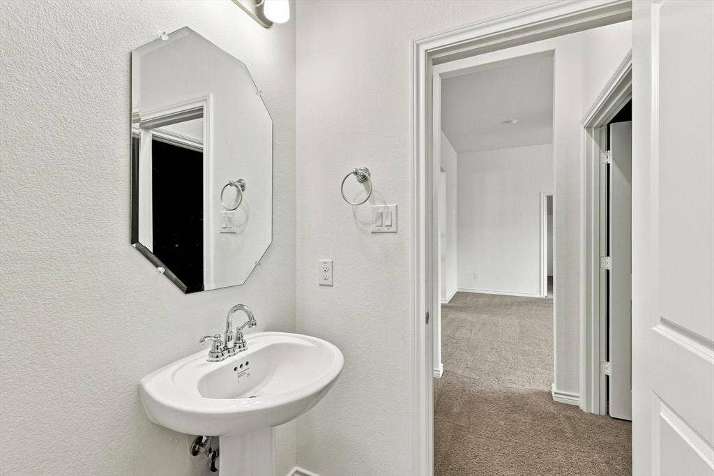 2812 Dunbar Drive, Northlake, TX 76247 Pedestal sink with chrome faucet, octagonal frameless mirror, and overhead vanity light