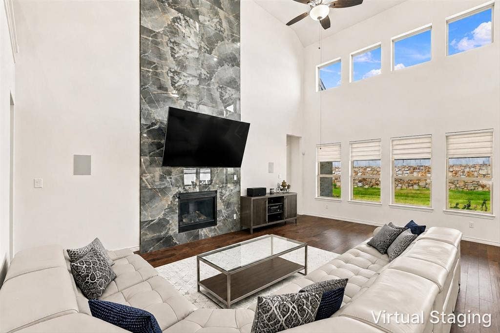 2812 Dunbar Drive, Northlake, TX 76247 Vaulted ceilings with a ceiling fan, a fireplace with a full-height stone surround, wood-finish flooring, and multiple windows
