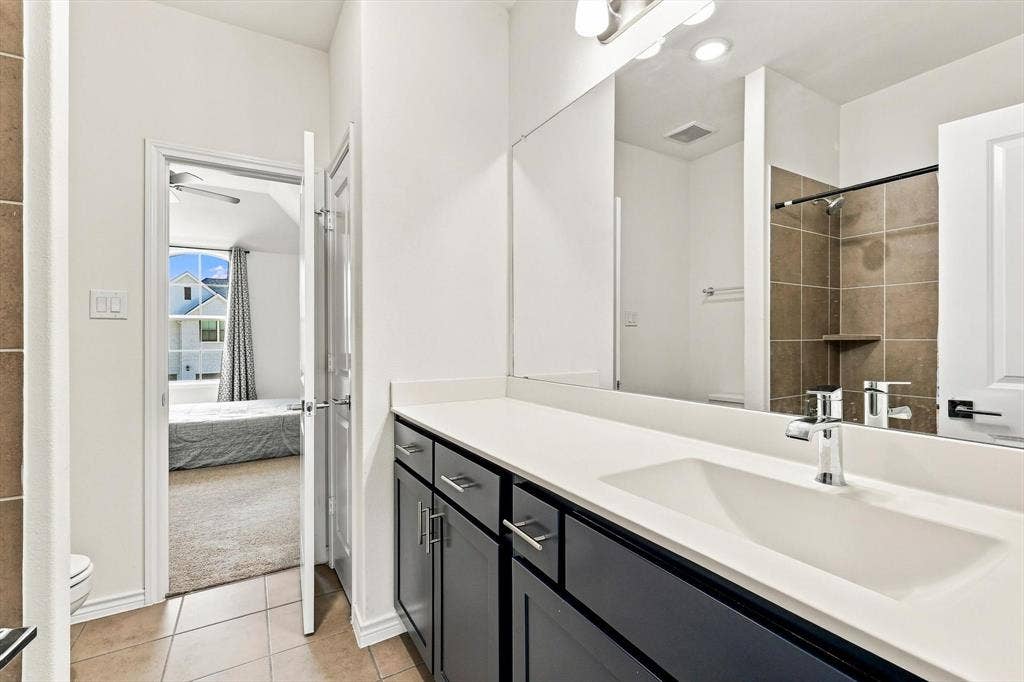 2812 Dunbar Drive, Northlake, TX 76247 Dual-basin vanity with a white countertop and dark cabinetry, featuring a large wall-mounted mirror and chrome fixtures