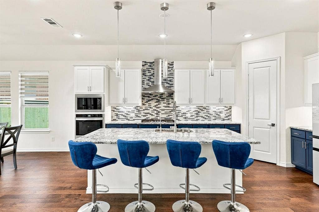 2812 Dunbar Drive, Northlake, TX 76247 Kitchen featuring a central island with a light-toned countertop, wood-finish flooring, two-toned cabinetry, and stainless steel appliances