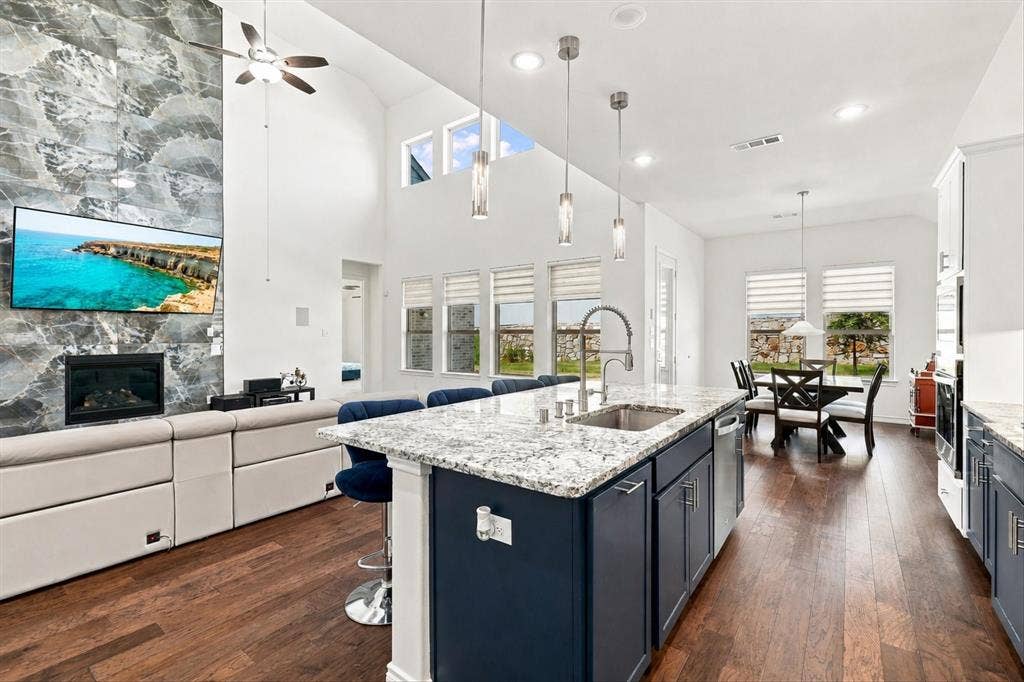 2812 Dunbar Drive, Northlake, TX 76247 Expansive living area with vaulted ceilings, a floor-to-ceiling stone-clad fireplace, and multiple windows