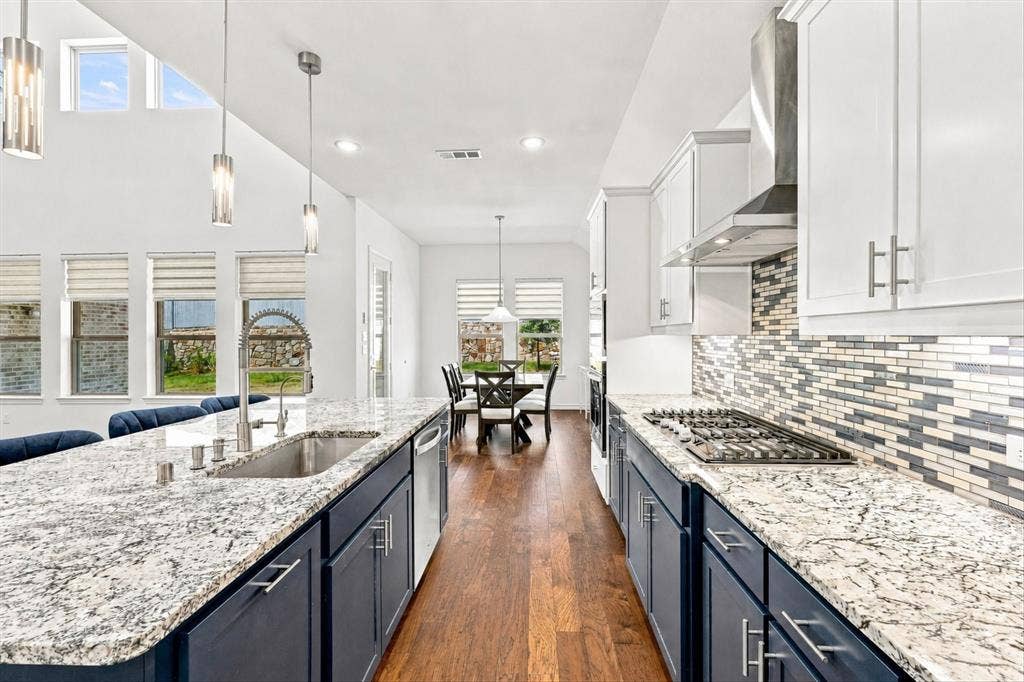 2812 Dunbar Drive, Northlake, TX 76247 Kitchen featuring a gas cooktop, stainless steel range hood, mosaic tile backsplash, wood-finish flooring, and pendant lighting
