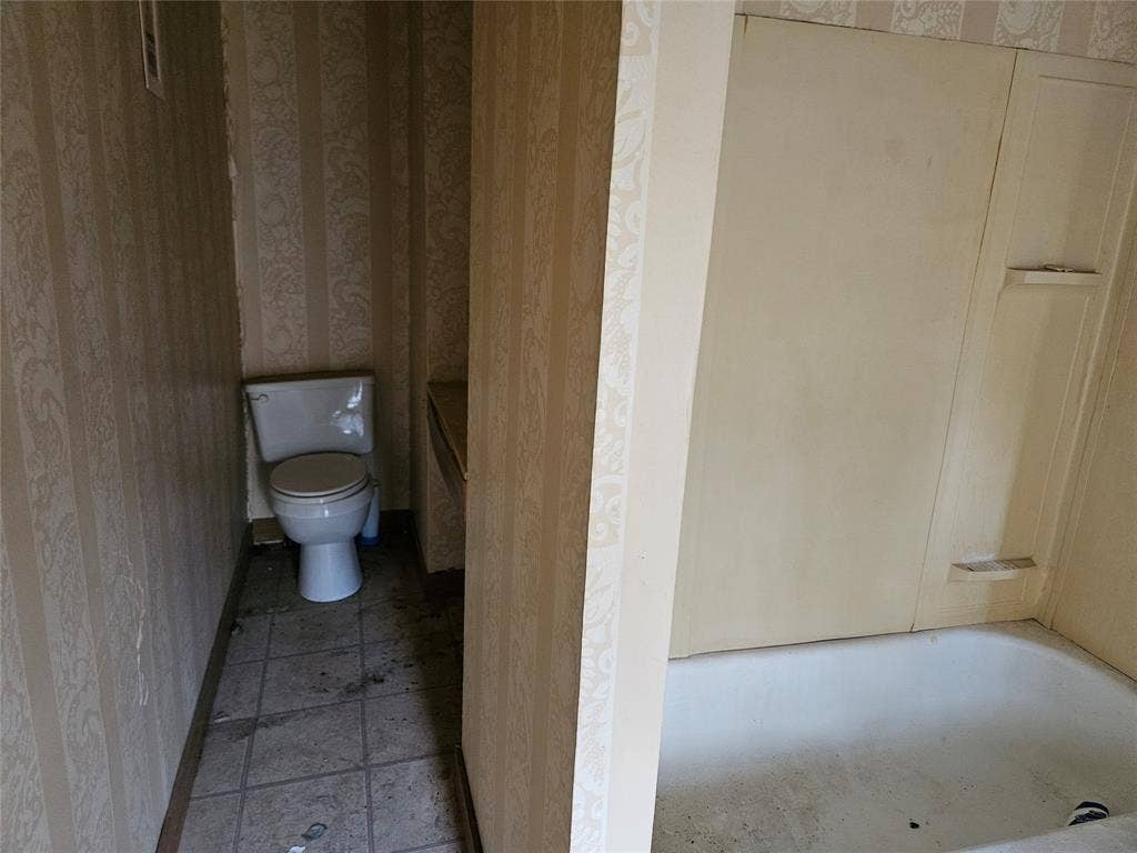 716 Dogwood Street, Robinson, TX 76706 Bathroom with wallpapered walls, a tub to relax in, and light tile patterned floors