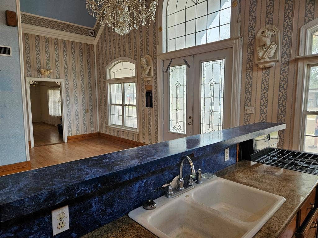 716 Dogwood Street, Robinson, TX 76706 Kitchen featuring wallpapered walls, a chandelier, and wood finished floors