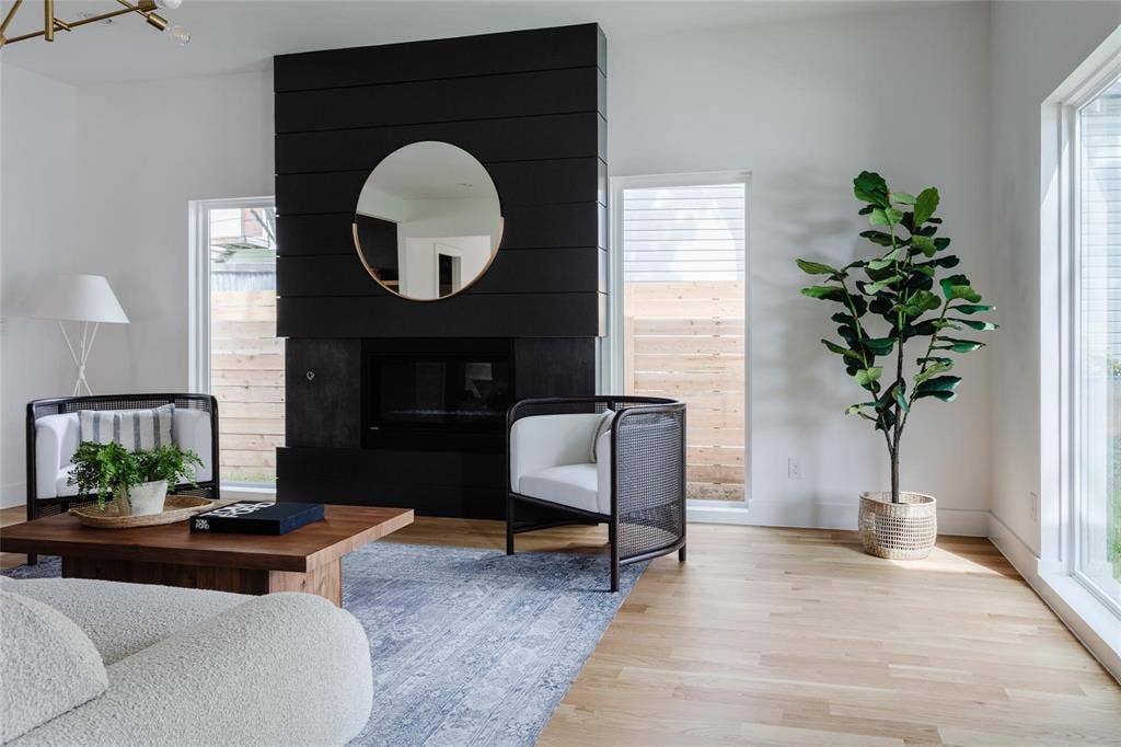 939 N Buckner Boulevard, Dallas, TX 75218 Black shiplap fireplace with a dark firebox, light wood-finish flooring, and expansive windows