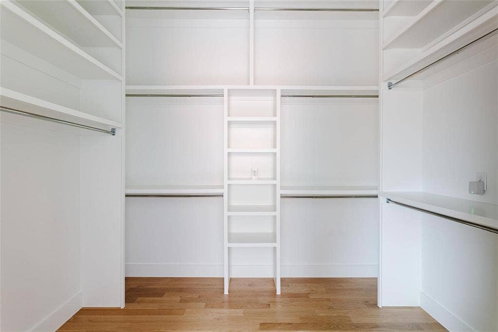 939 N Buckner Boulevard, Dallas, TX 75218 Built-in white shelving system with multiple hanging rods, integrated shelving units, and wood-finish flooring