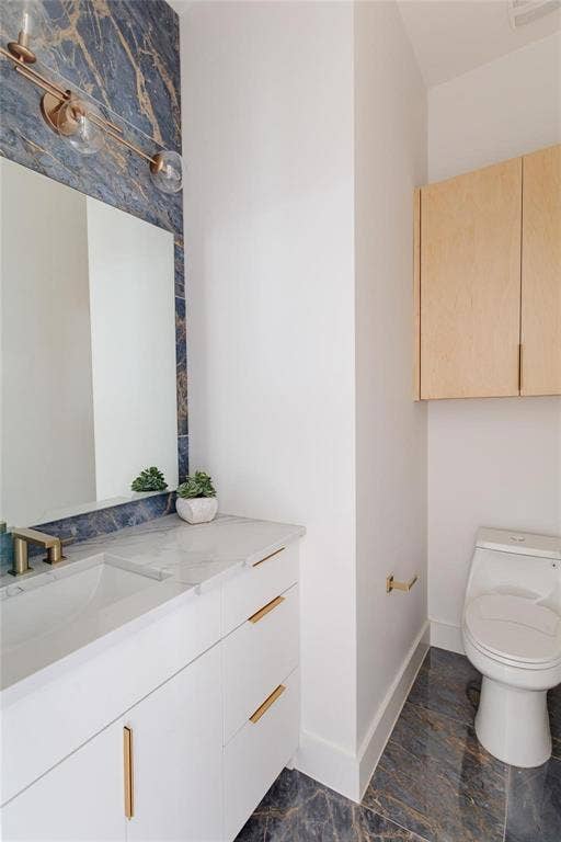 939 N Buckner Boulevard, Dallas, TX 75218 Built-in vanity with a single basin sink, gold-finish hardware, and a marble-pattern countertop
