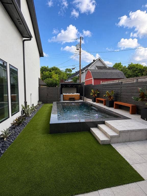 939 N Buckner Boulevard, Dallas, TX 75218 Contemporary backyard featuring a rectangular pool with dark tile surround, integrated steps, and surrounding patio pavers