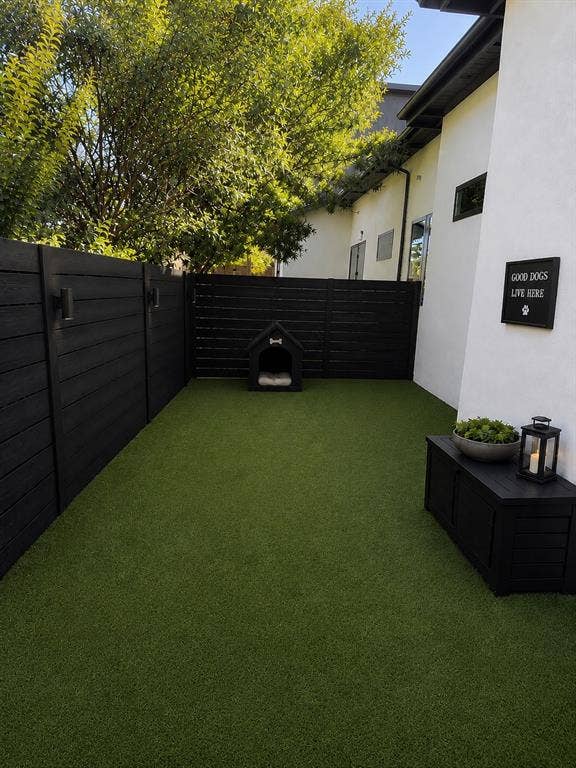 939 N Buckner Boulevard, Dallas, TX 75218 Private dog run outdoor space featuring artificial turf and dark-stained fencing with integrated lighting