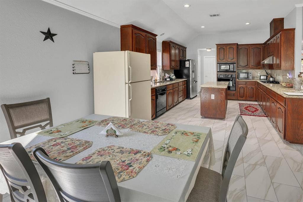 1506 Park Grove Drive, Irving, TX 75060 Spacious kitchen featuring wood cabinetry, light-toned countertops, a central island, built-in appliances, and light-colored tile flooring