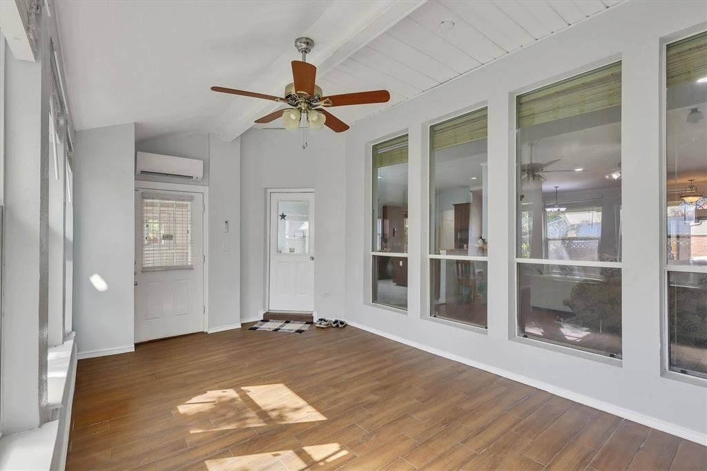 1506 Park Grove Drive, Irving, TX 75060 Wood-finish flooring with multiple windows, two exterior doors, a ceiling fan, and a wall-mounted mini-split unit