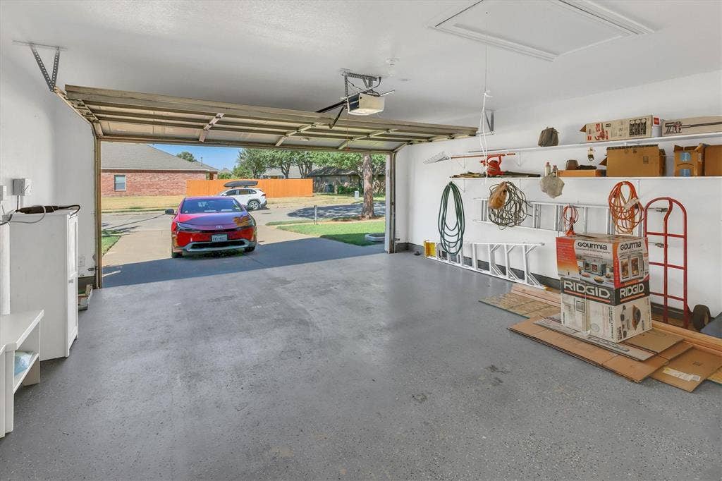 1506 Park Grove Drive, Irving, TX 75060 Attached garage with epoxy-coated flooring, built-in shelving, and an automatic garage door opener